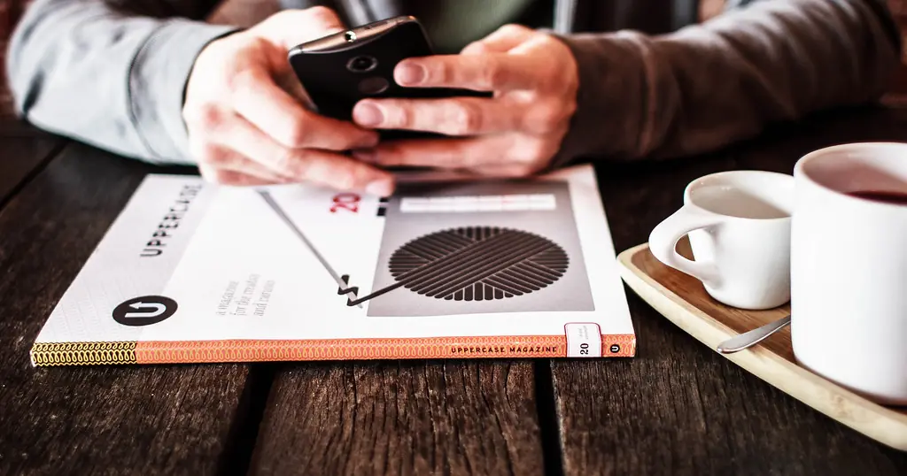 Comment trouver un plan cul: un téléphone tenu au-dessus d'une table de café