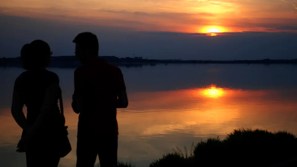 Rencontre plan cul à Bulle: les silhouettes d’un couple au bord de l’eau au crépuscule