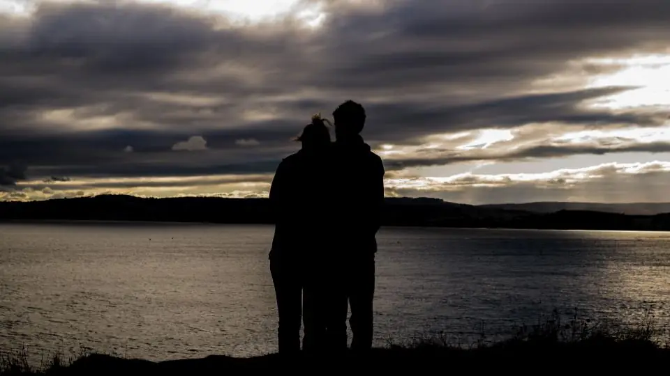 Rencontre plan cul à Sion: un couple enlacé face au lac sous un ciel du soir