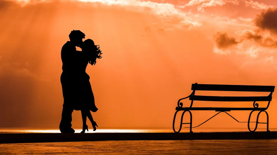 Rencontre plan cul en Valais: le baiser d’un couple en silhouette sur un ciel orangé
