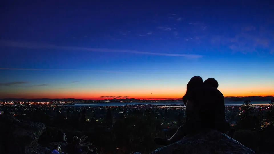 Site de rencontre adulte: un couple enlacé face à la ville au crépuscule