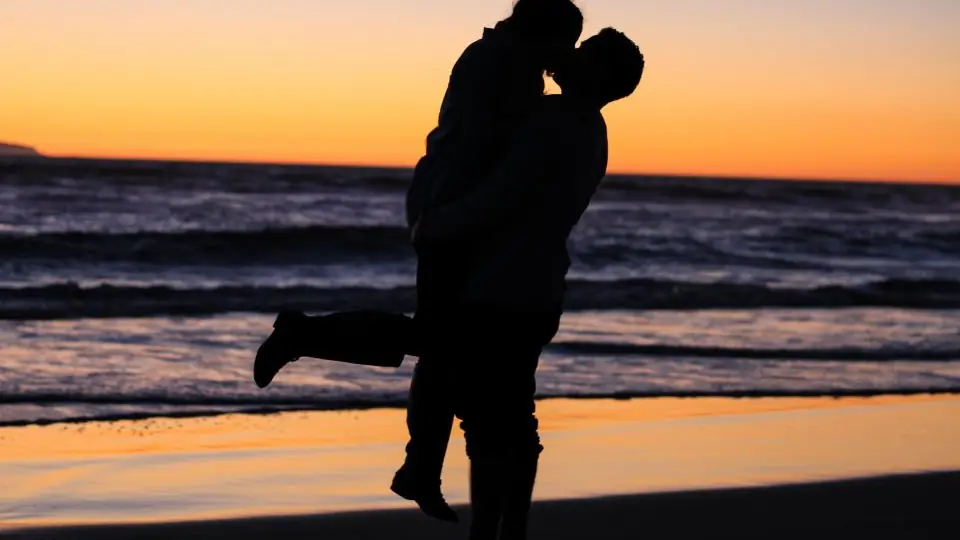 Plan cul ou rencontre classique: un couple s’embrasse au bord de la mer au coucher du soleil