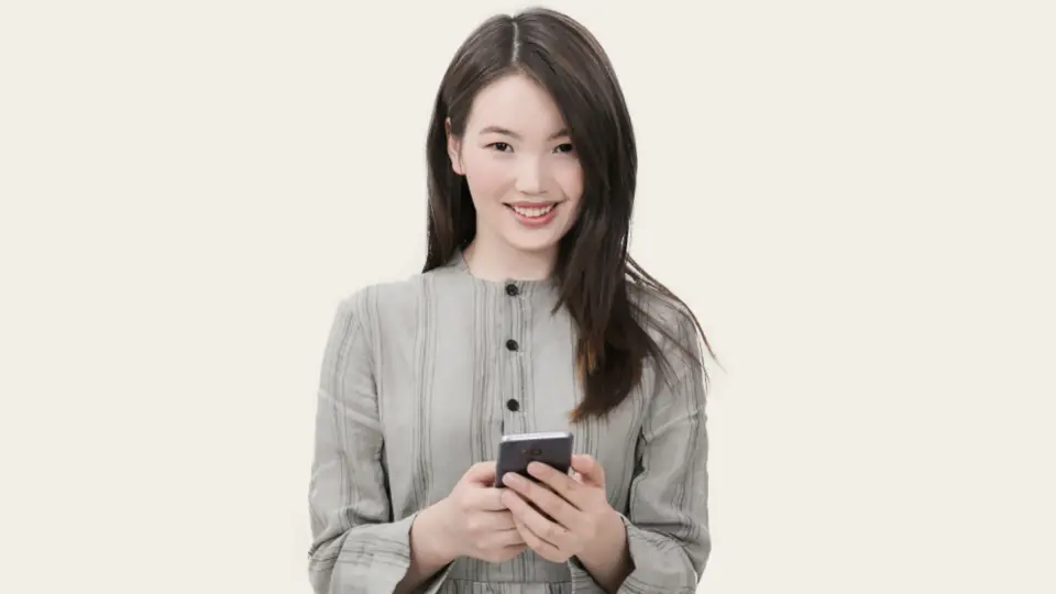 Une femme sourit en regardant son téléphone avant un rendez-vous
