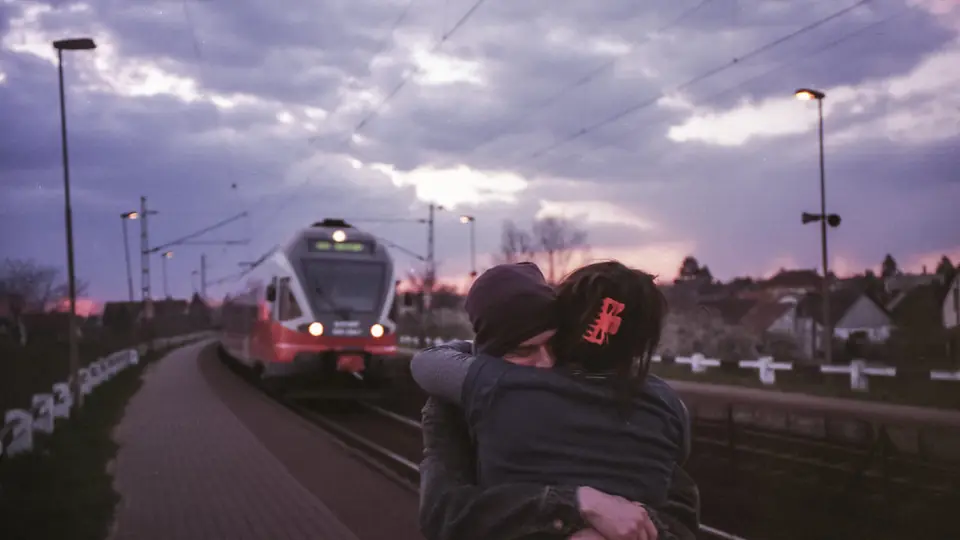 Un couple s'embrasse tendrement sur un quai de gare
